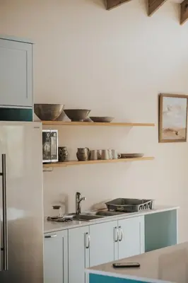 a kitchen with white cabinets and a stainless steel refrigerator at Sandown Synergy Lagoon House in Hermanus