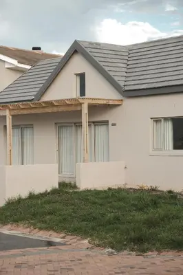 a white house with a black roof at Sandown Synergy Lagoon House in Hermanus