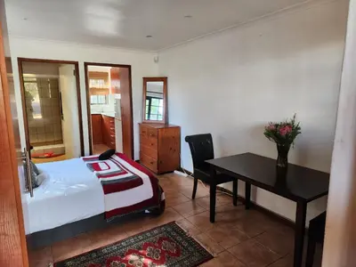 a bedroom with a bed and a desk and a table at Cape Cottage in Cape Town