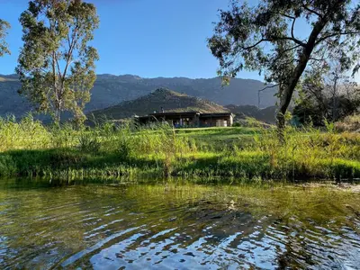 a house on a hill next to a body of water at Underhill Cottage in Breerivier