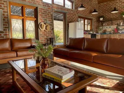 a living room with a couch and a glass table at Underhill Cottage in Breerivier