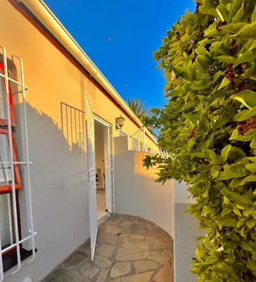 a building with a green hedge next to a door at 3 Bedroom Family Home with Pool in Cape Town