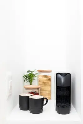 a shelf with two coffee cups and a laptop at Nine Palms 223B in Cape Town