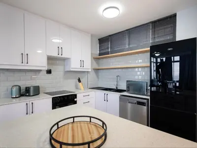 a kitchen with white cabinets and a black refrigerator at St Tropez Beachfront 306 in Strand
