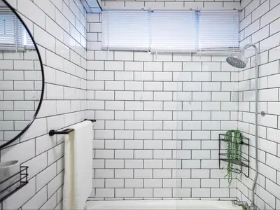 a white tiled bathroom with a tub and a window at St Tropez Beachfront 306 in Strand