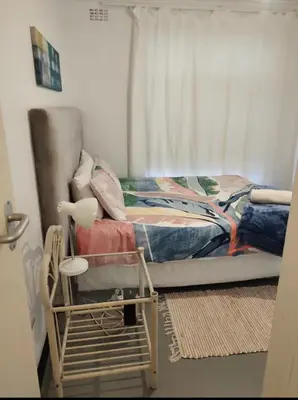 a small bedroom with a bed and a window at Claremont Studio in Cape Town