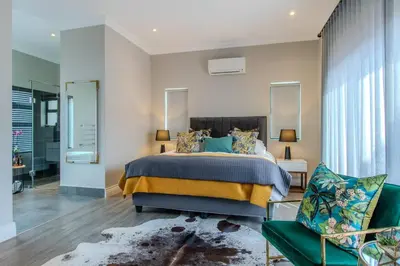 a bedroom with a large bed and a green chair at Songbird D'Aria Cape Town luxury house on Wine Estate in Cape Town