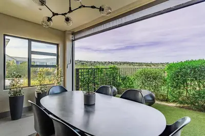 a dining room with a table and chairs and a large window at Songbird D'Aria Cape Town luxury house on Wine Estate in Cape Town