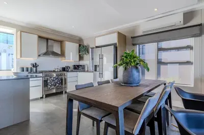 a kitchen and dining room with a wooden table and chairs at Songbird D'Aria Cape Town luxury house on Wine Estate in Cape Town