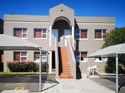 a building with two umbrellas in front of it at Smithland Centrally Located Accommodation in Cape Town