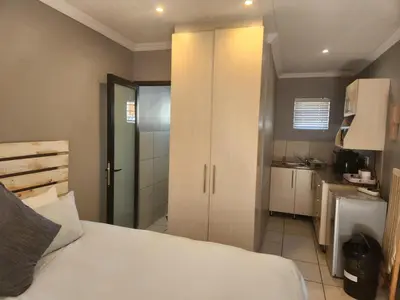 a bedroom with a white bed and a kitchen at Smithland Centrally Located Accommodation in Cape Town