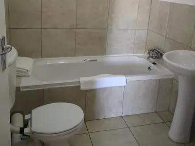 a bathroom with a toilet and a tub and a sink at Smithland Centrally Located Accommodation in Cape Town