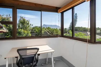 a desk and chair in a room with windows at Green Haven Apartment in Milnerton in Cape Town