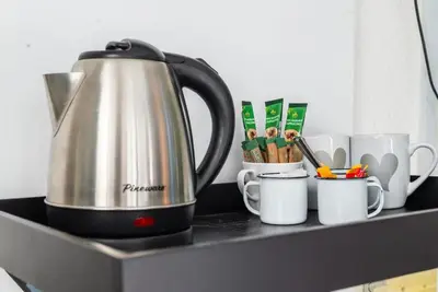 a tea kettle on a counter with cups and utensils at Platinum Haven Aparment in Milnerton in Cape Town