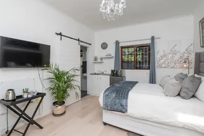 a white bedroom with a bed and a table at Platinum Haven Aparment in Milnerton in Cape Town