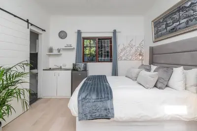 a bedroom with a large white bed and a kitchen at Platinum Haven Aparment in Milnerton in Cape Town
