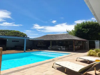 a swimming pool with two chairs and a house at Cape Select Luxury Accommodation in Durbanville