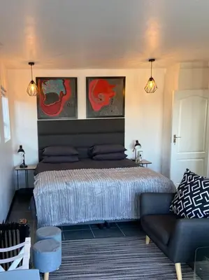 a bedroom with a bed and a couch and paintings at 31Ridge Road in Durbanville