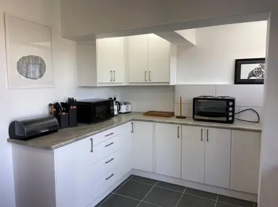 a kitchen with white cabinets and black appliances at 31Ridge Road in Durbanville