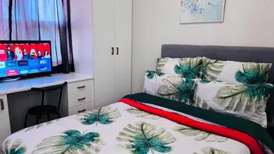 a bedroom with a bed and a desk with a computer at Leisure Lodges selfcatering accommodation Parow in Cape Town