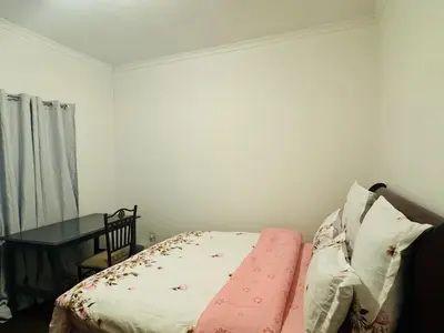 a small bedroom with a bed and a table at Leisure Lodges selfcatering accommodation Parow in Cape Town