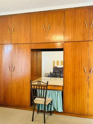 a room with a desk with a chair and wooden cabinets at Leisure Lodges selfcatering accommodation Parow in Cape Town