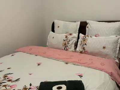 a bed with pink and white sheets and pillows at Leisure Lodges selfcatering accommodation Parow in Cape Town