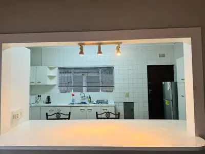 a kitchen with white cabinets and a refrigerator at Leisure Lodges selfcatering accommodation Parow in Cape Town