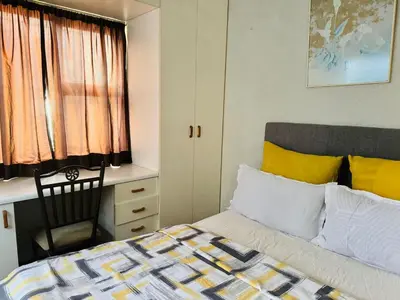 a bedroom with a bed and a desk and a chair at Leisure Lodges selfcatering accommodation Parow in Cape Town