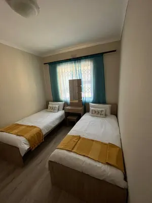two beds in a small room with a window at Alucia in Cape Town