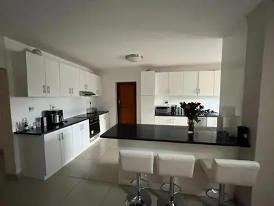 a kitchen with white cabinets and a black counter top at Alucia in Cape Town