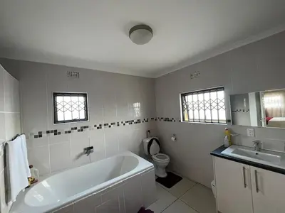 a white bathroom with a tub and a toilet at Alucia in Cape Town