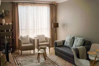 a living room with a couch and chairs and a window at Spacious 1 Bedroom Flat Church St Stellenbosch in Stellenbosch