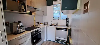 a small kitchen with white appliances and a window at Stylish 2-Bed Flat with Exclusive Patio - Easy Access to Cape Town Highlights in Cape Town