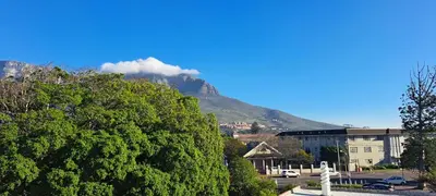 a mountain in the background with a building and a tree at Stylish 2-Bed Flat with Exclusive Patio - Easy Access to Cape Town Highlights in Cape Town