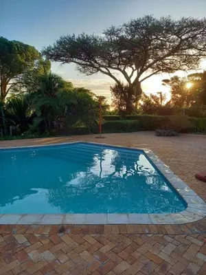 a swimming pool in a yard with a sunset at Somer House Guest Suites in Somerset West