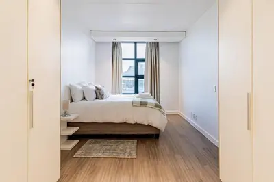 a white bedroom with a bed and a window at 1 bed flat with Mountain view in Cape Town