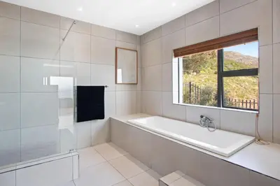 a white bathroom with a tub and a window at Restio View 11 in Cape Town