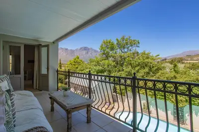 a porch with a couch and a table on a balcony at Luxury Five Bed House in the Heart of Franschhoek in Franschhoek