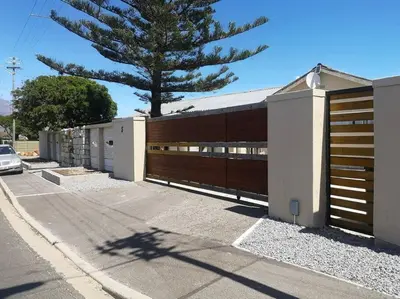 a house with a wooden fence and a tree at Coastal Cozy Home in Cape Town