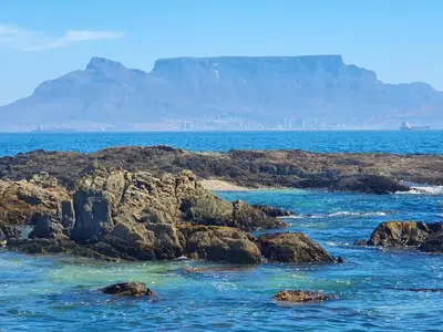 a view of the ocean with a mountain in the background at Bloubergstrand Beachfront Apartment Witsand 101 in Cape Town