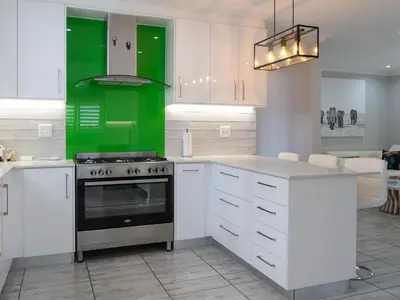 a kitchen with white cabinets and a green island at Vida Tranquilo in Edgemead