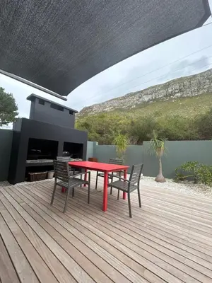 a red table and chairs on a wooden deck at Villa Silver Vos in Hermanus