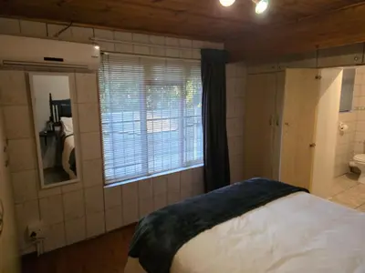 a bedroom with a bed and a window and a bathroom at Urban Retreat in Cape Town