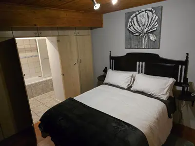 a bedroom with a large bed and a bathroom at Urban Retreat in Cape Town