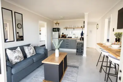 a living room with a blue couch and a kitchen at Ocean Whisper Unit 79 in Hermanus