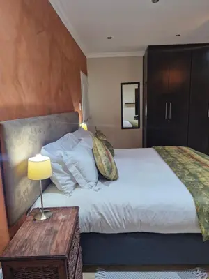 a bedroom with a large white bed and a table at Lumley's Place Guesthouse in Pniel