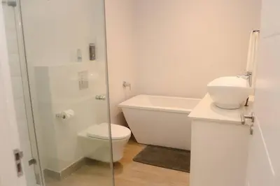 a white bathroom with a toilet and a sink at 24 Le Bourgette in Franschhoek