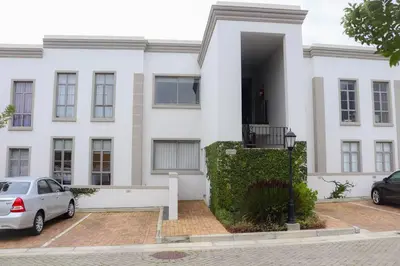 a white house with a car parked in front of it at 24 Le Bourgette in Franschhoek