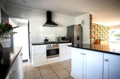 a kitchen with white cabinets and a stove top oven at Happy Hideaway in Hermanus
